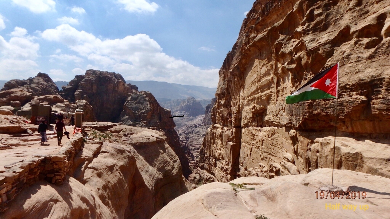 Vue panoramique sur un canyon avec un drapeau jordanien qui flotte au vent.