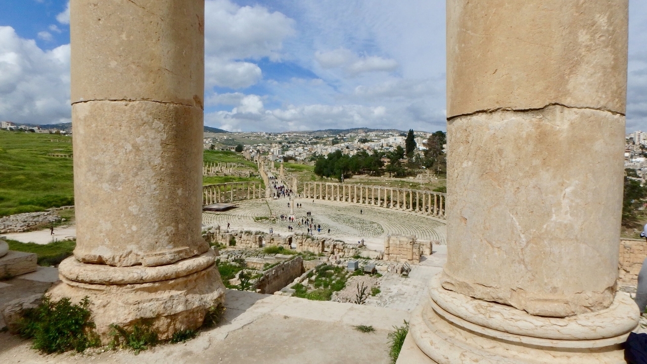 Ruines antiques avec des colonnes de pierre surplombant une vaste place.