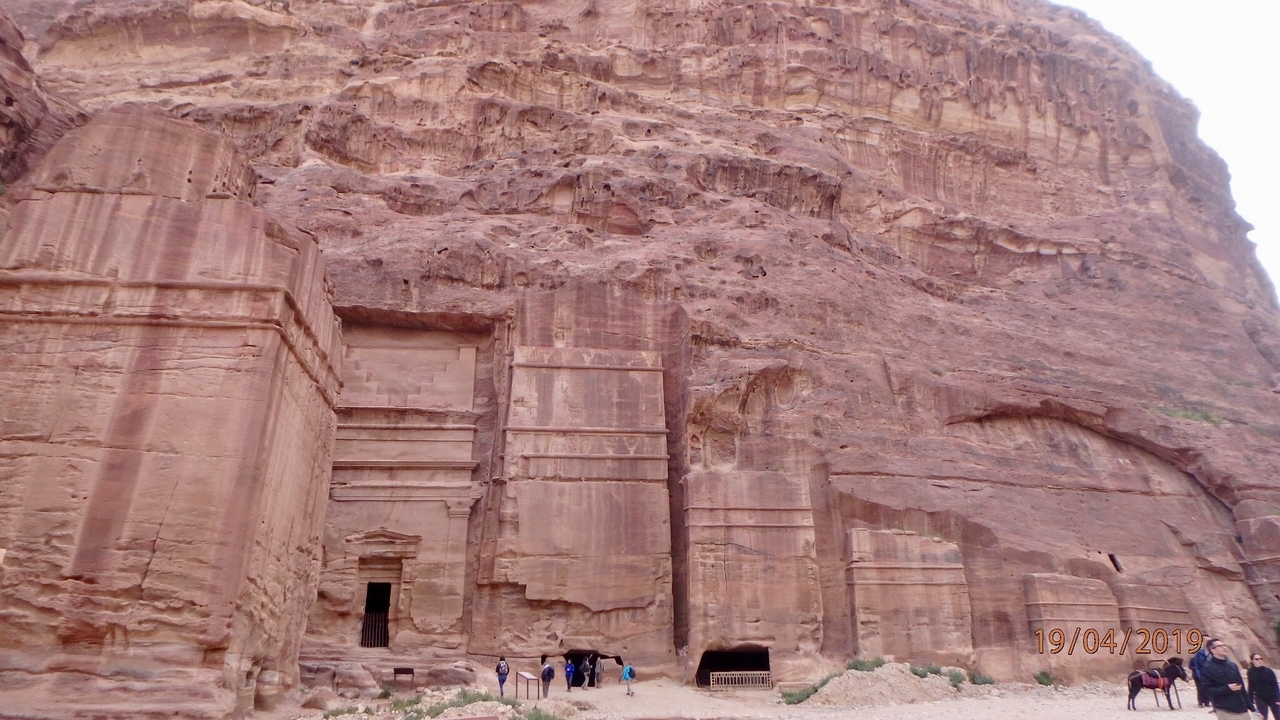 Grandes formations rocheuses avec des touristes explorant un site archéologique.