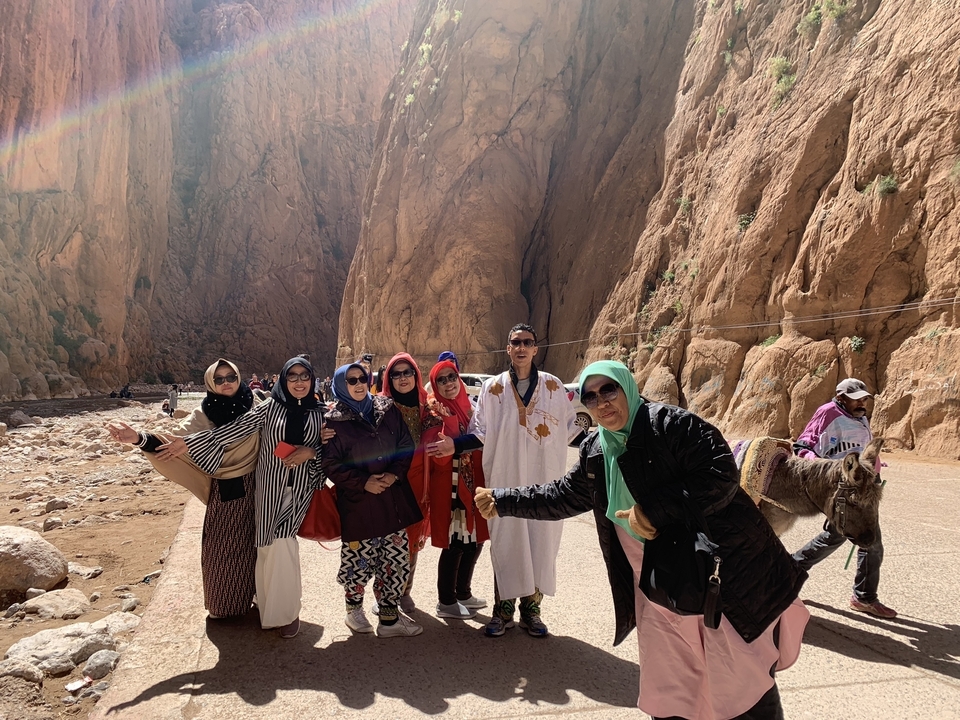 Group of people posing in front of a rocky canyon wall.