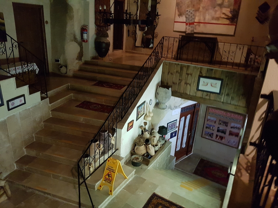 Zone d'entrée avec escaliers et décorations en poterie.