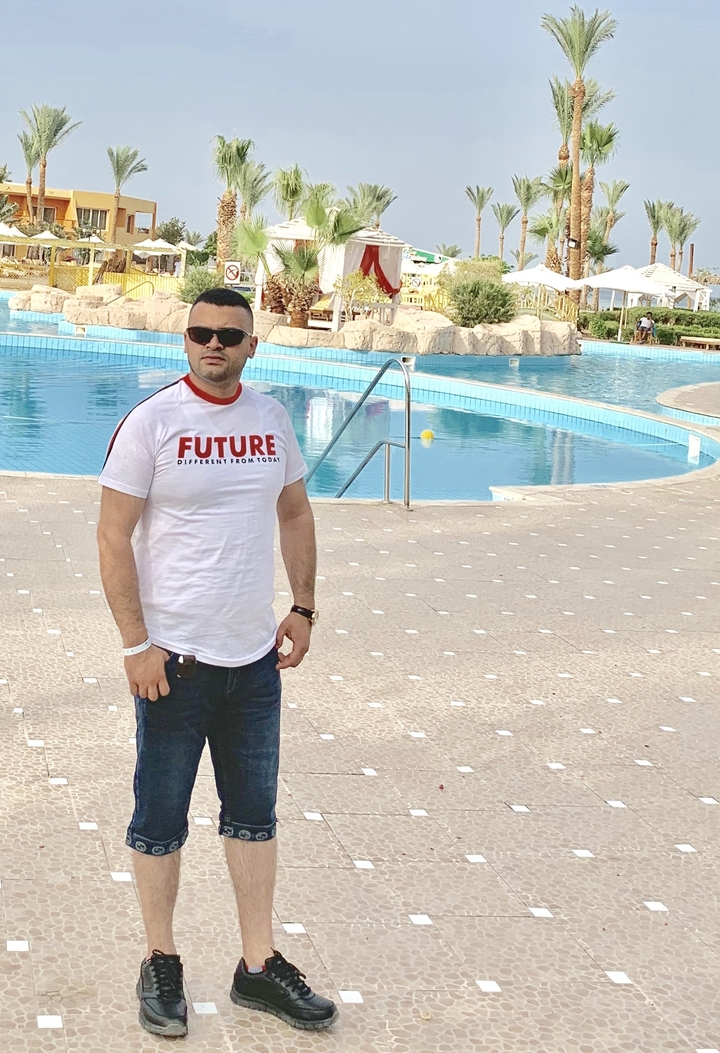 Homme posant près d'une piscine.