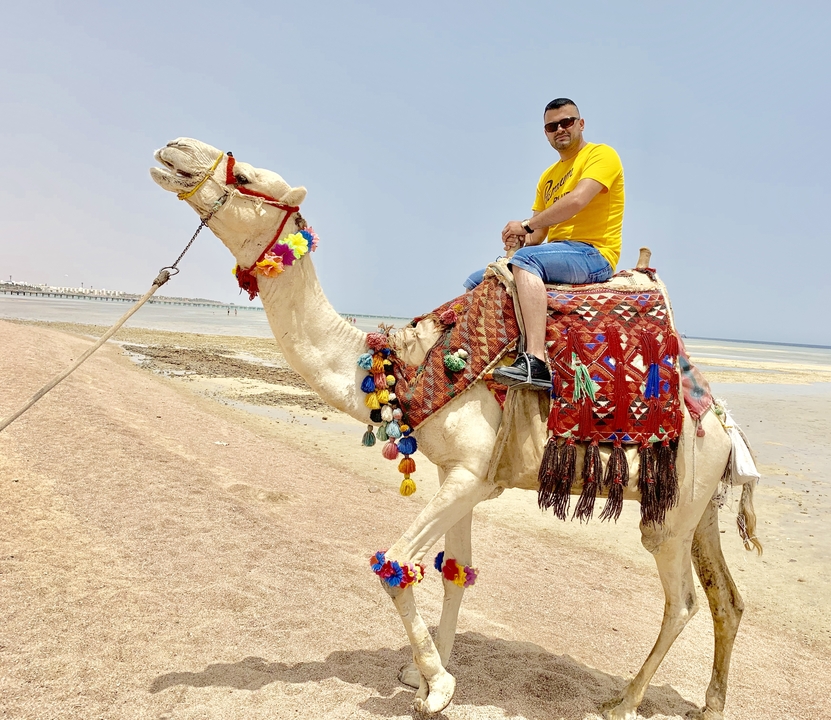 Un homme montant un chameau sur une plage.