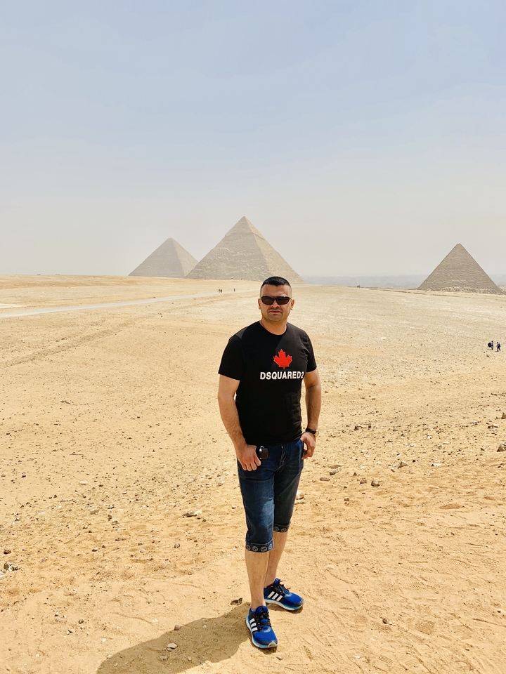 Un homme qui pose avec les pyramides de Gizeh au loin.