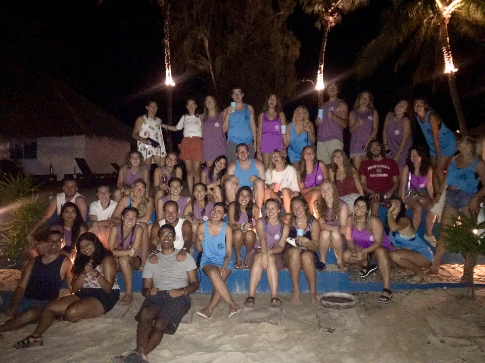 Large group photo taken at night with people posing and cheering.