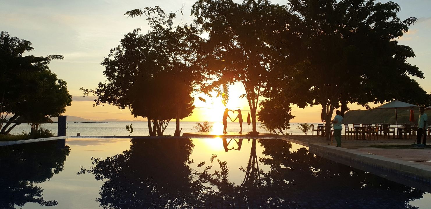 Silhouette of a couple forming a heart shape during sunset.