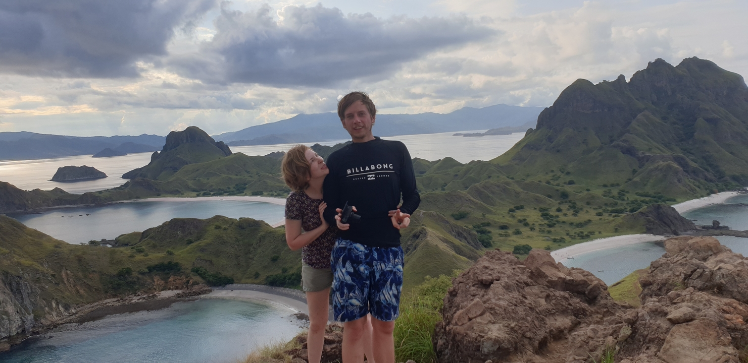 Couple standing on a hill overlooking islands and ocean.