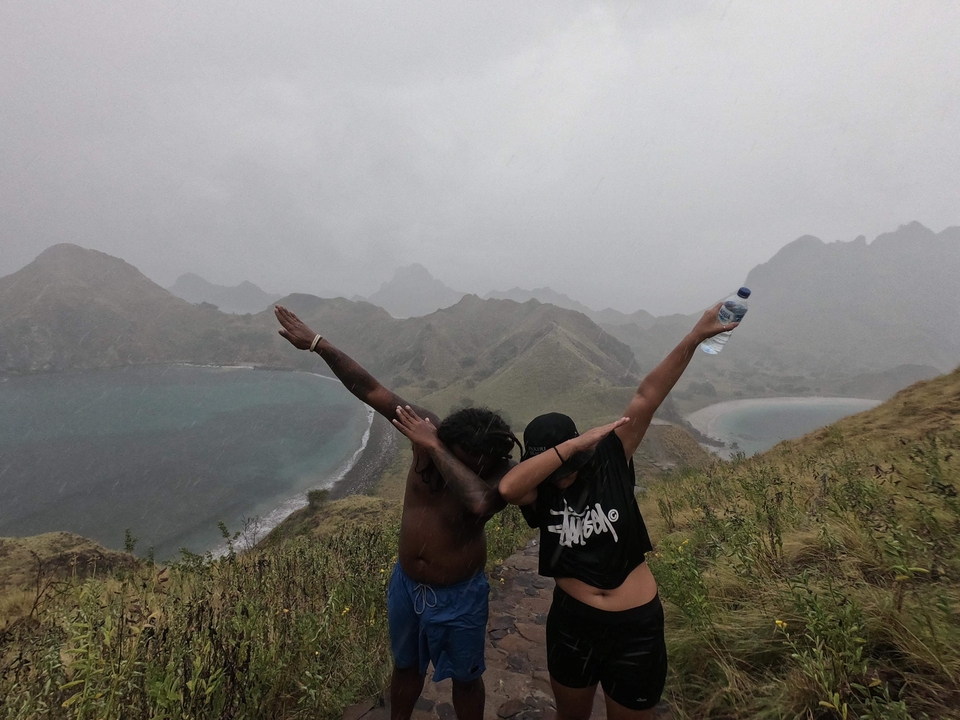 Deux personnes posant de manière ludique sur une colline pittoresque.