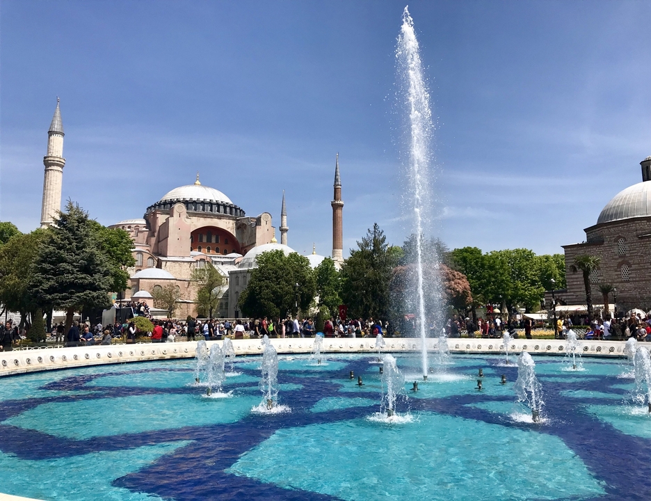 Fountain and historic architecture with people walking.