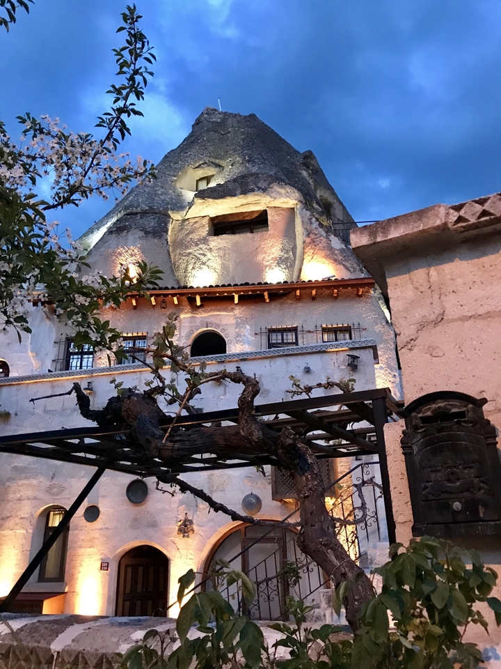 Illuminated cave hotel exterior in evening light.