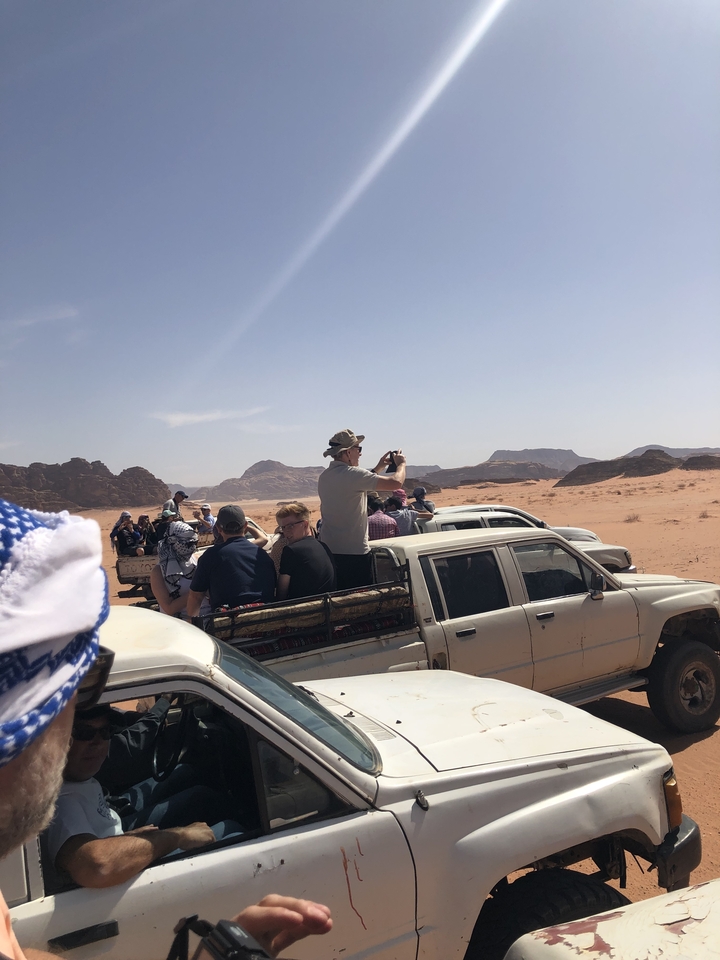 People standing on pickup trucks in the desert landscape