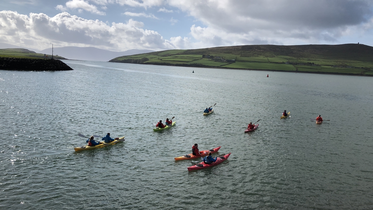 Group kayaking on calm water with hills in the background
