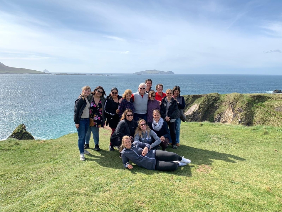 Group of people on a grassy cliffside with ocean background