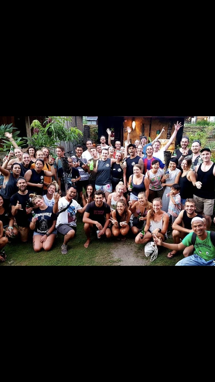 Large group of people posing together with drinks in a garden.