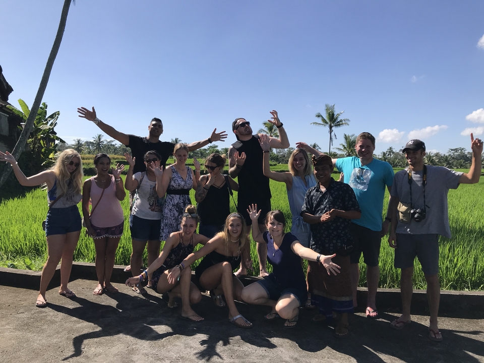 Cheerful group posing with a background of rice paddies.