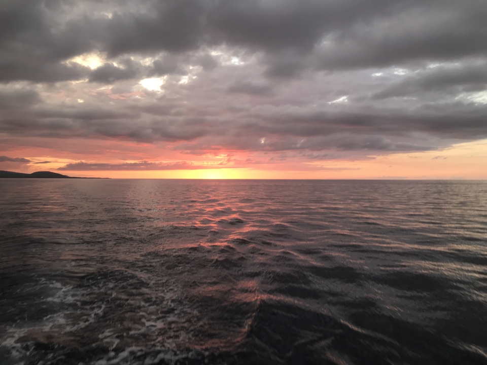 Ocean sunset with dramatic clouds and reflective water.