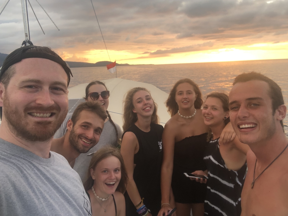 Group selfie on a boat during sunset with an ocean view.