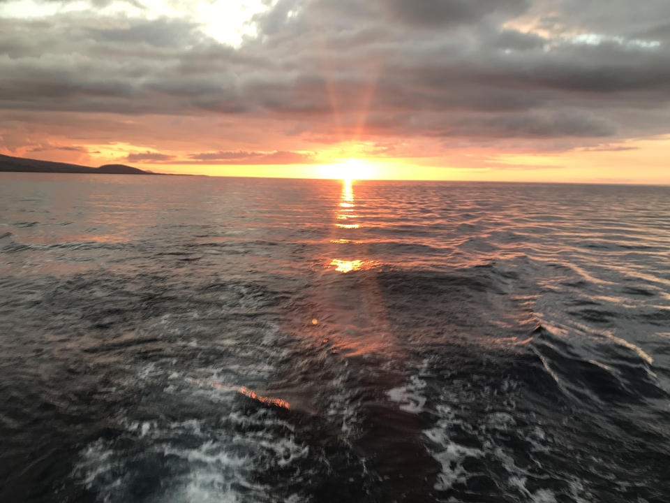 Coucher de soleil sur l'océan avec des eaux agitées.