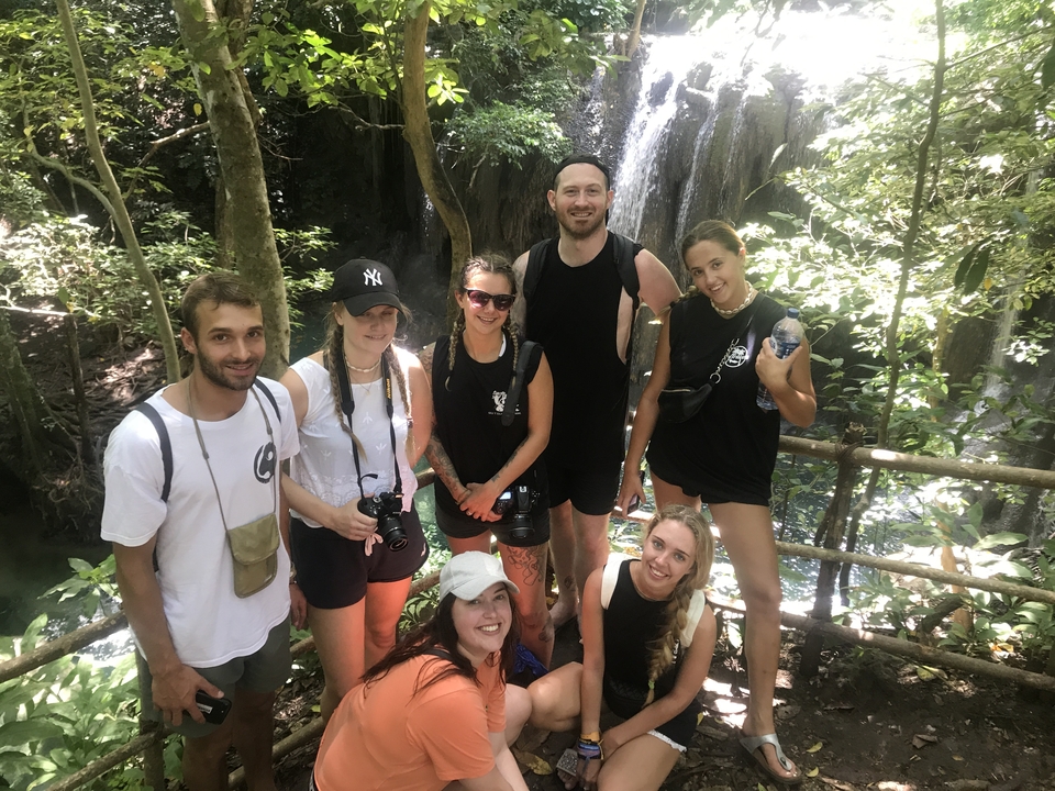 Groupe de personnes posant devant une cascade dans un cadre forestier.
