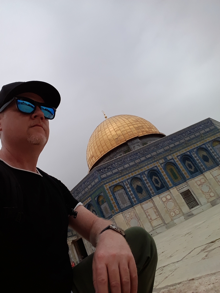 Person posing near a golden-domed building.