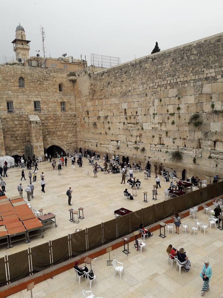 People gathered at an ancient wall, engaged in various activities.