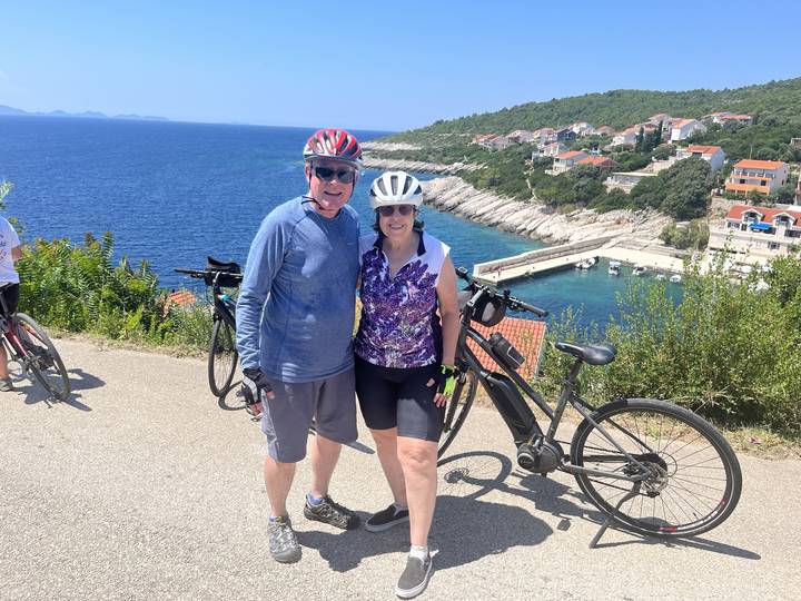 Deux personnes avec des vélos surplombant un littoral.