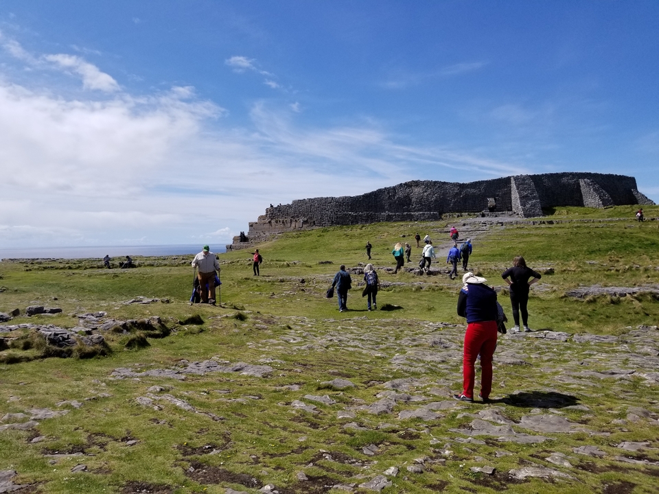 Tourists exploring ancient stone ruins in an open grassy area.