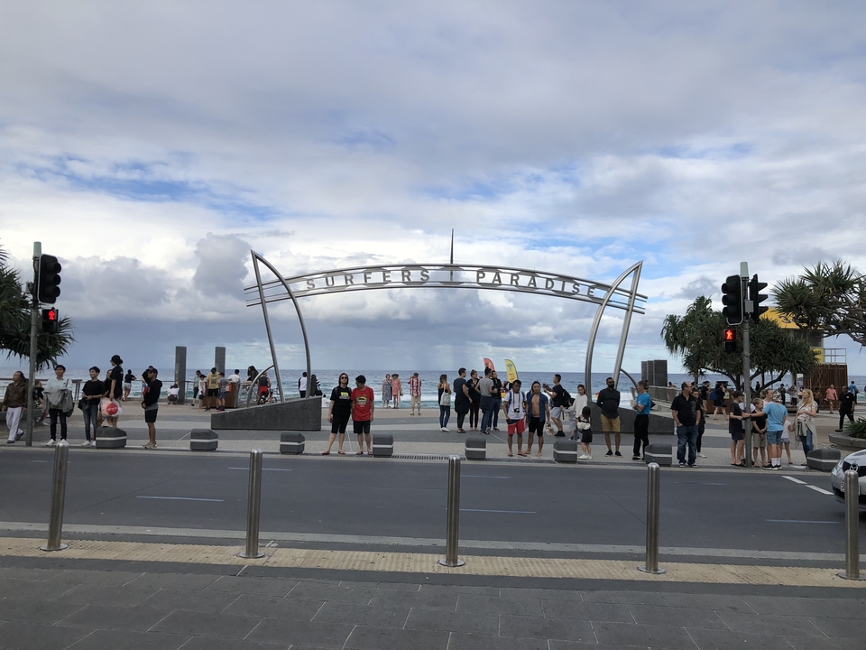 Surfers Paradise sign with people nearby at the beach area.
