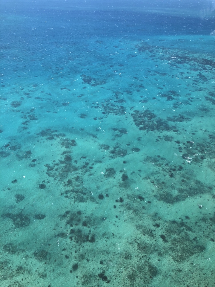 Aerial view of turquoise waters with visible underwater patterns.