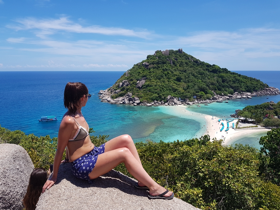 Woman sitting on rocks overlooking the sea and island.