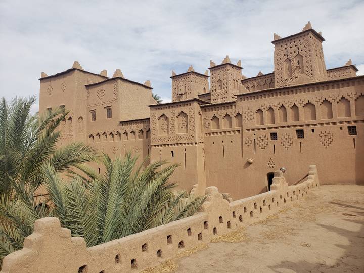 Bâtiment traditionnel de style adobe avec palmiers.