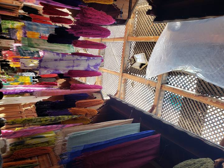 Scène de marché avec des textiles colorés dans un espace couvert.