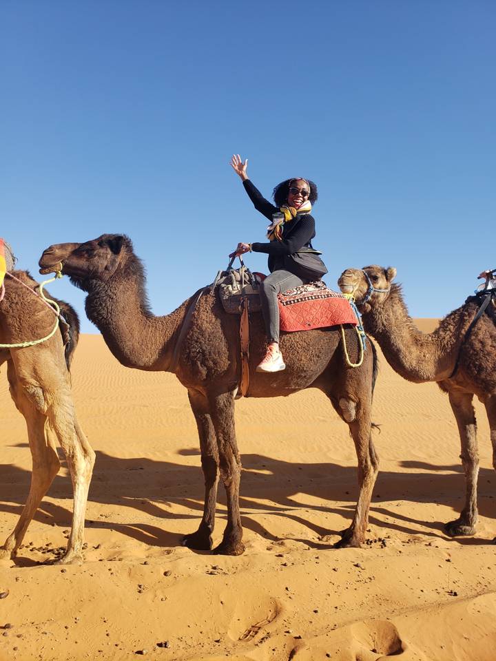 Personne montant un chameau dans le désert avec un sourire.