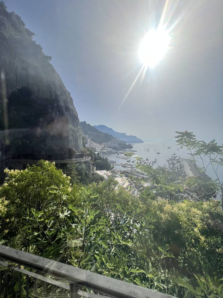 Bright sun over a landscape with trees and distant hills.