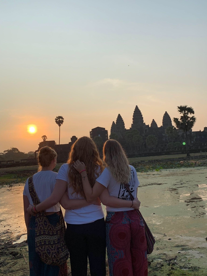 Three women looking towards Angkor Wat during sunrise.