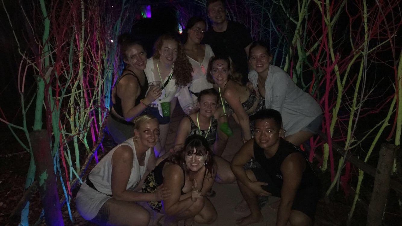 Group of friends enjoying a vibrant night out with colorful lights.