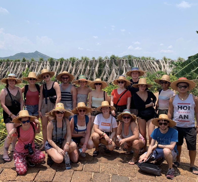 Group of tourists posing in a garden area with mountains.