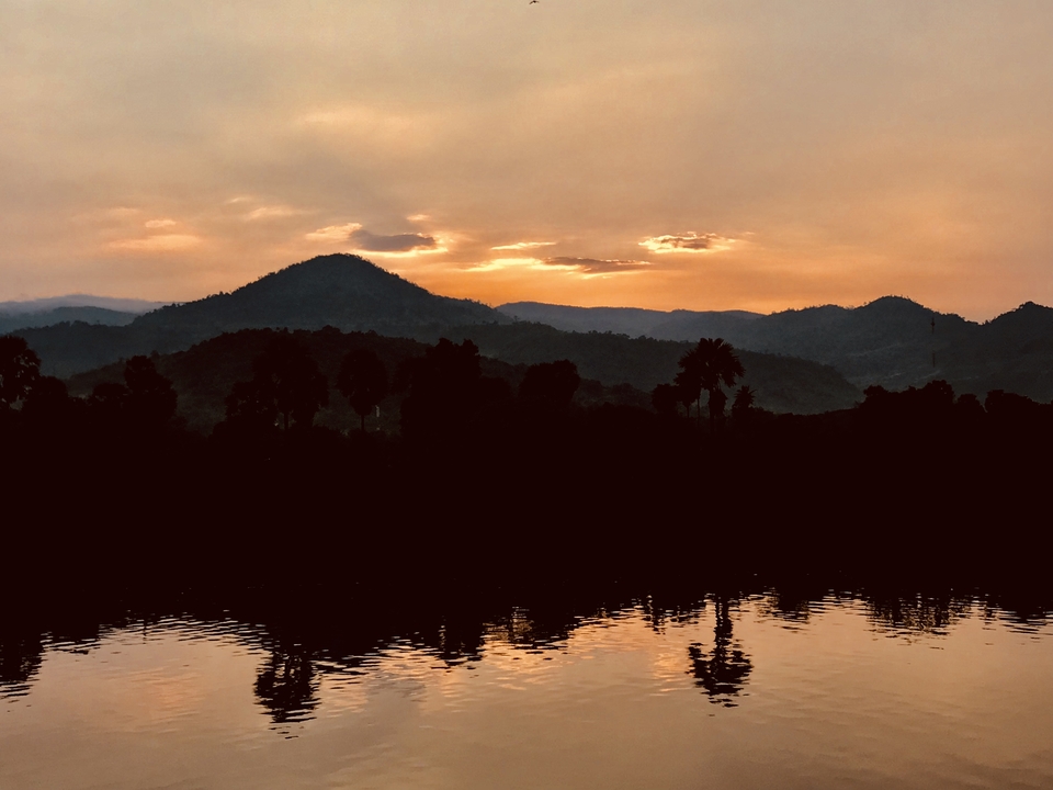 Dramatic sunset over hills and reflected on water.