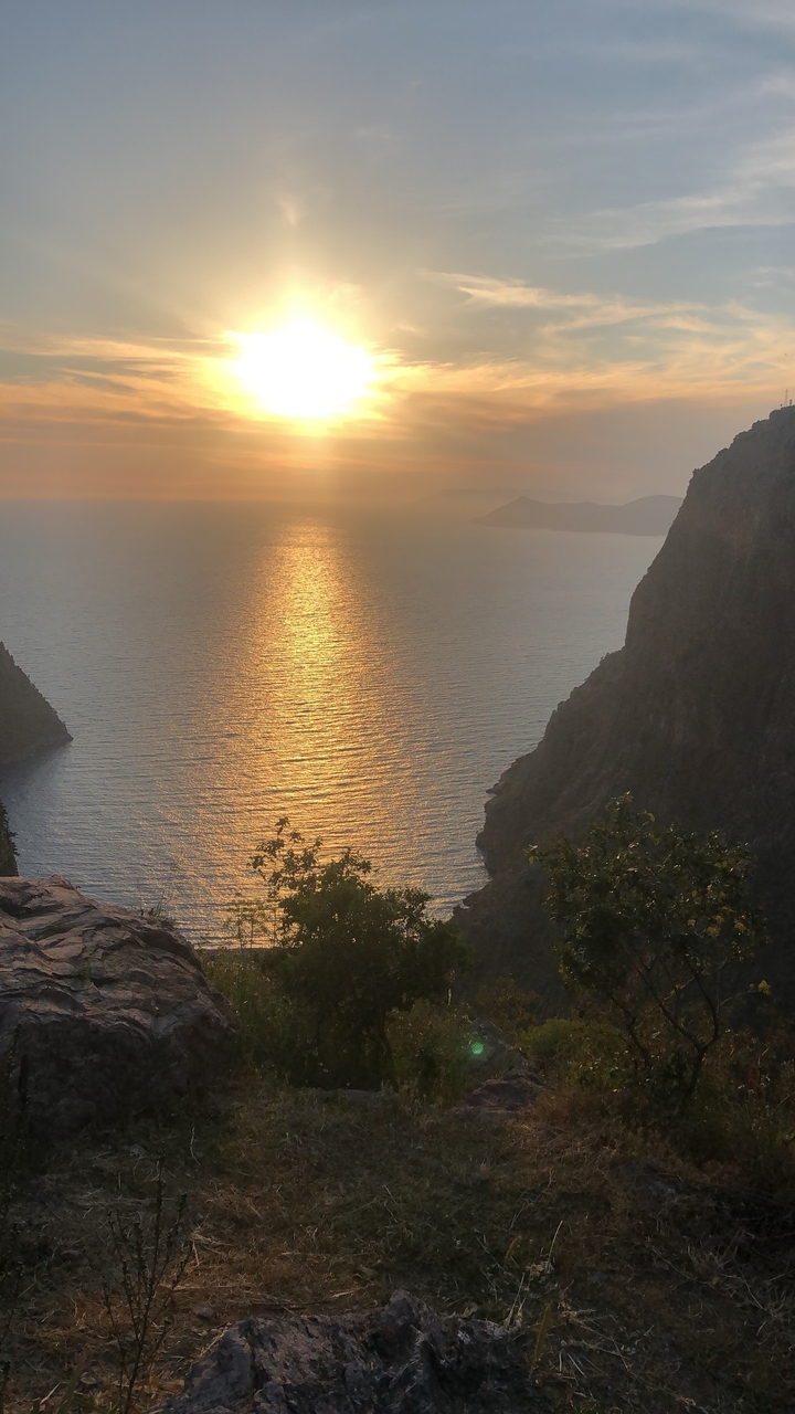 Vue de coucher de soleil sur un plan d'eau avec des falaises de chaque côté.