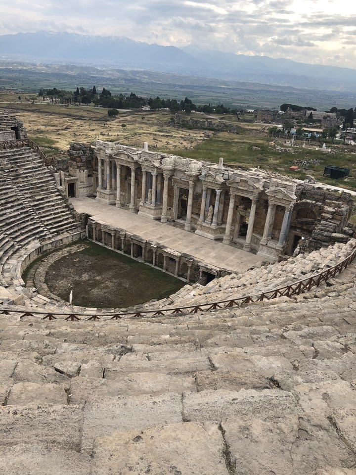 Ruines d'un amphithéâtre antique avec des gradins en pierre.