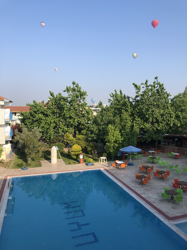 Vue au bord de la piscine avec montgolfière en arrière-plan.
