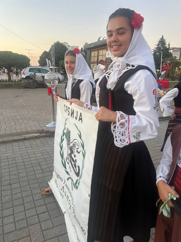 Men and women in traditional attire holding a banner.
