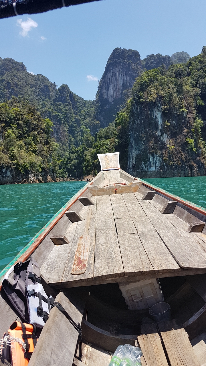 Vue depuis un bateau se dirigeant vers une île rocheuse et verdoyante.