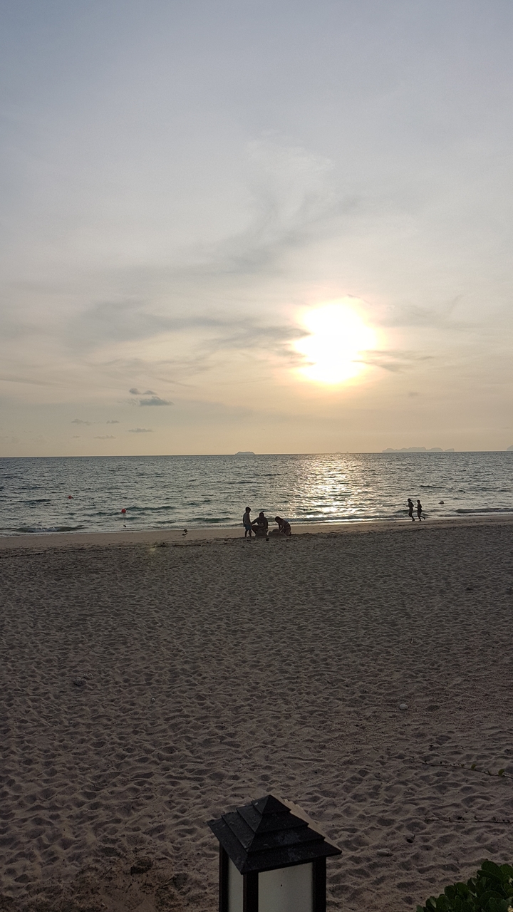 Des gens qui profitent du coucher de soleil sur une plage de sable.