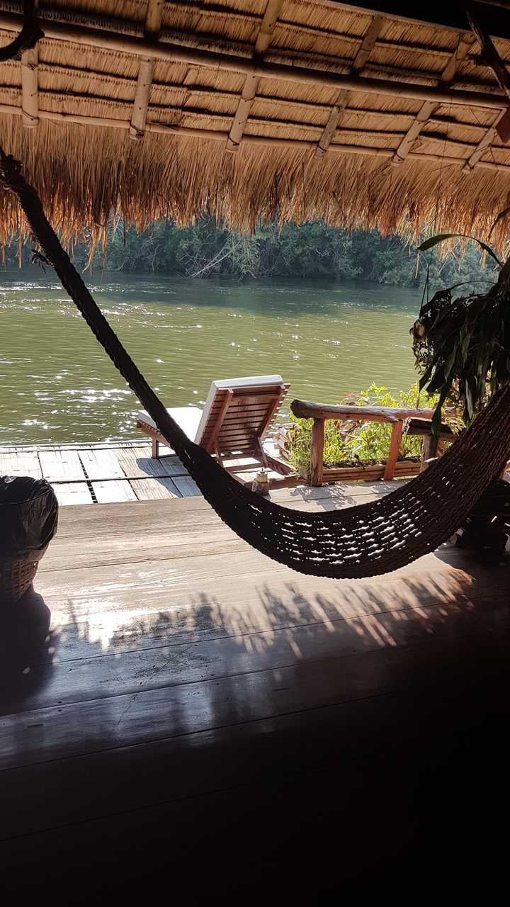 Ponton en bois avec un hamac et une chaise longue au bord de l'eau.