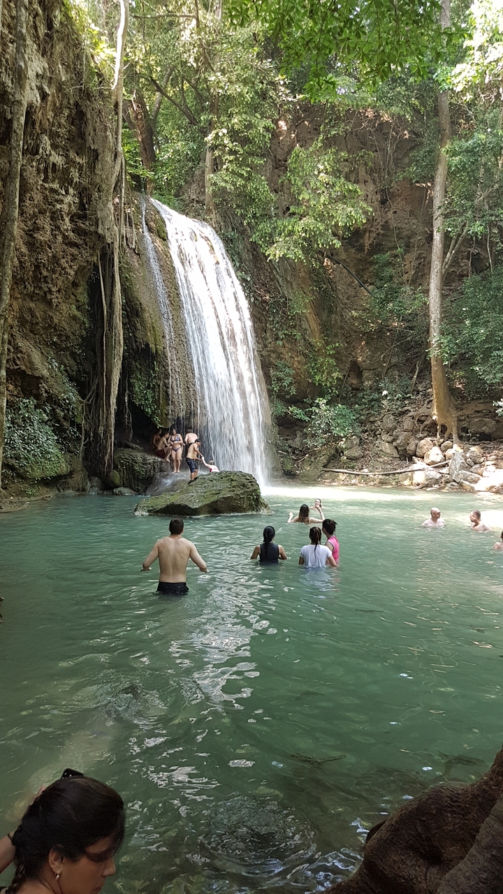 Des gens qui nagent et jouent dans un bassin naturel de cascade.