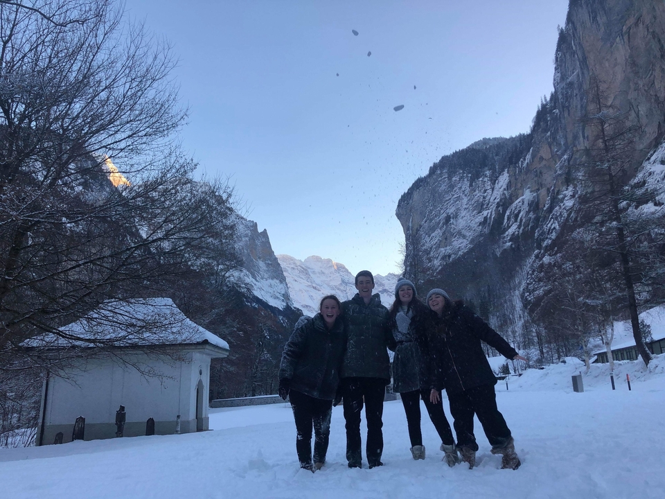 Group of people standing in a snowy mountainous landscape.