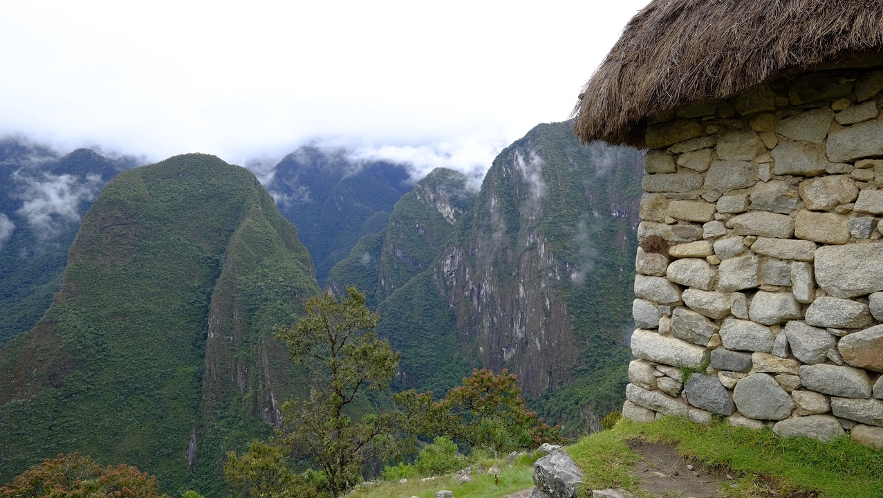 Stone structure with mountain view and greenery.