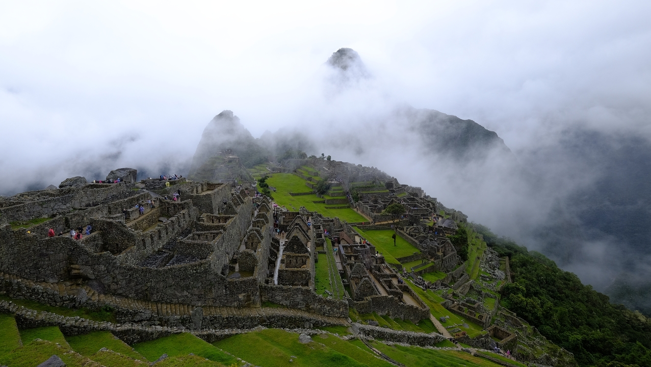 Panoramic view of Machu Picchu surrounded by misty mountains.