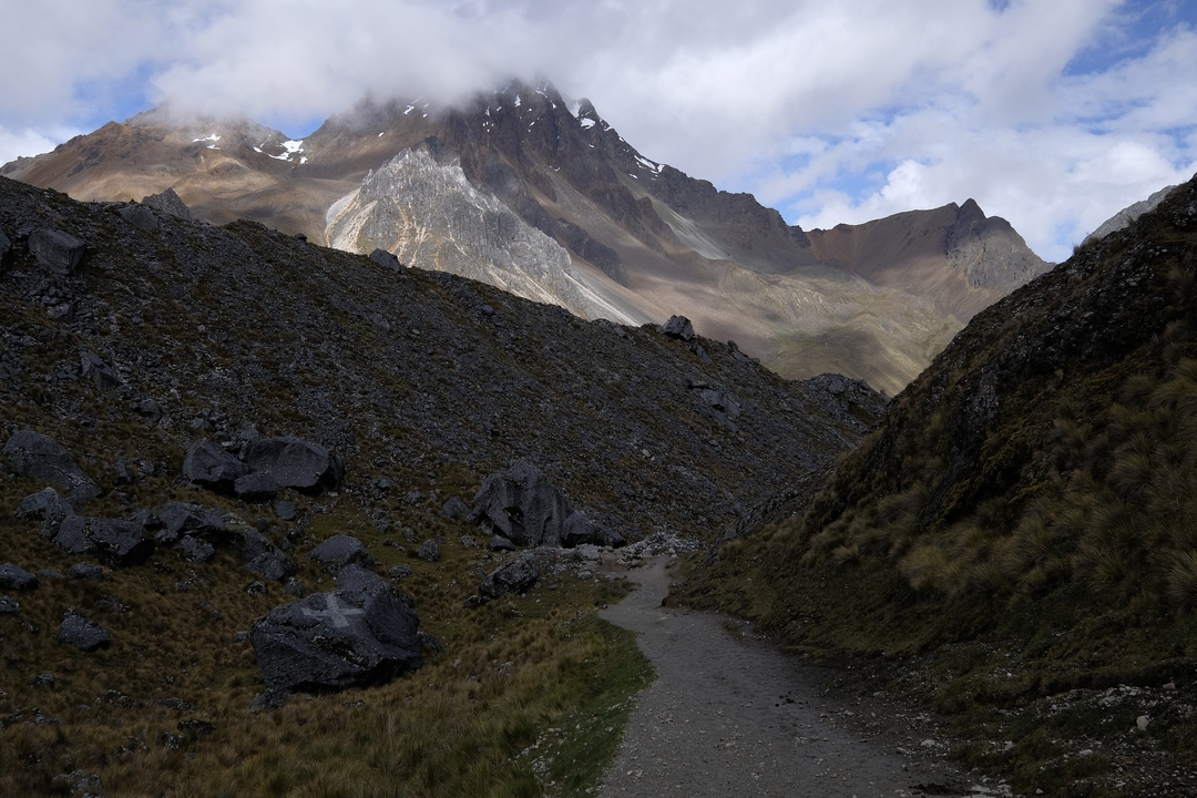 Mountain path with rocky terrain and clouds.